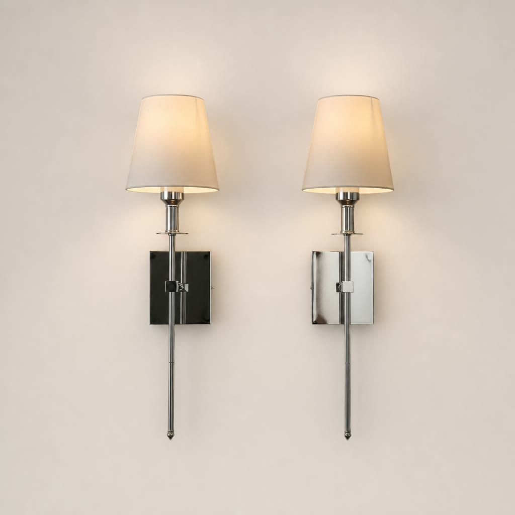 Two polished chrome wall sconces with cream fabric shades on a plain light background.