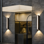 Two slim rectangular wall lights illuminate a gray brick storefront entrance.
