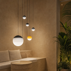 Five globe pendant lights hang over a beige lounge corner with plants nearby.