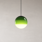 Green glass globe pendant light hanging from a black cord against a pale minimalist wall.