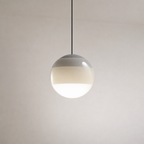 Glossy spherical pendant light with a black cord and warm glowing white lower half.