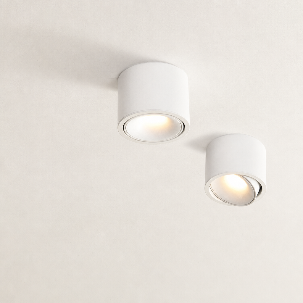 Two white cylindrical ceiling spotlights with warm recessed bulbs on a pale ceiling.