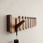 Wooden wall-mounted rail with staggered vertical blocks holding a dark angled lamp.