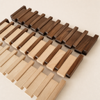 Interlocking light and dark wooden slat mats arranged diagonally on a pale surface.