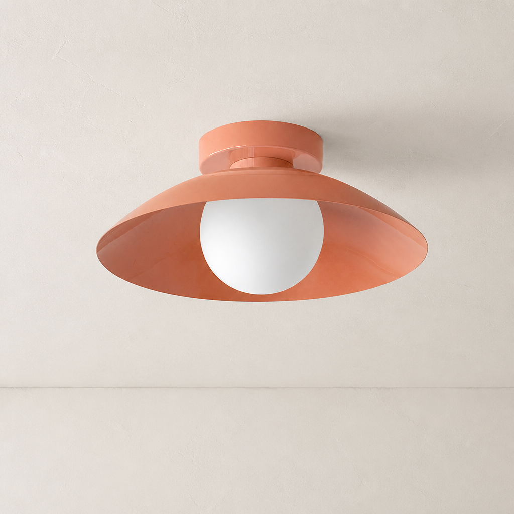 Coral ceiling light with wide saucer shade and white globe bulb on a pale ceiling.
