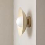 Cream wall sconce with a white globe bulb mounted on a neutral wall.