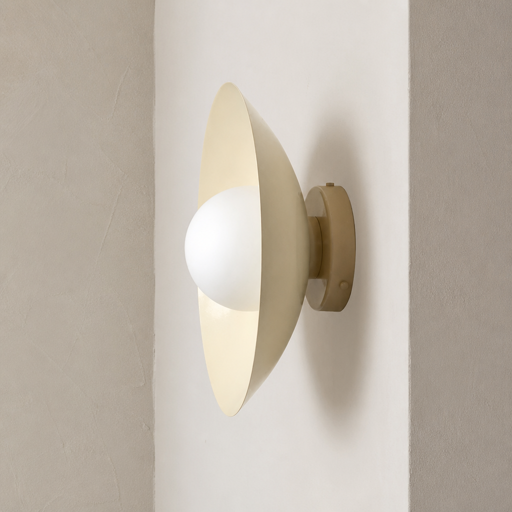 Cream wall sconce with a white globe bulb mounted on a neutral wall.