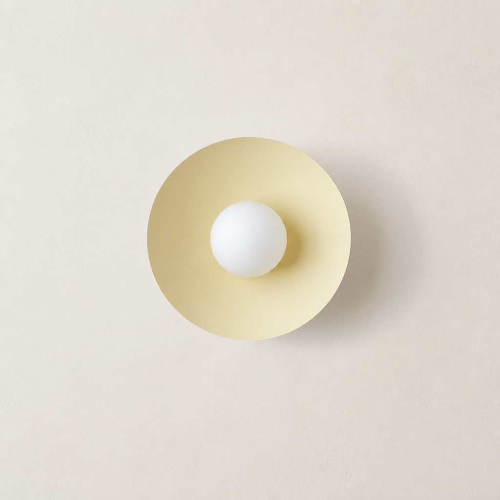 Cream circular wall sconce with a centered white globe bulb on a neutral wall.