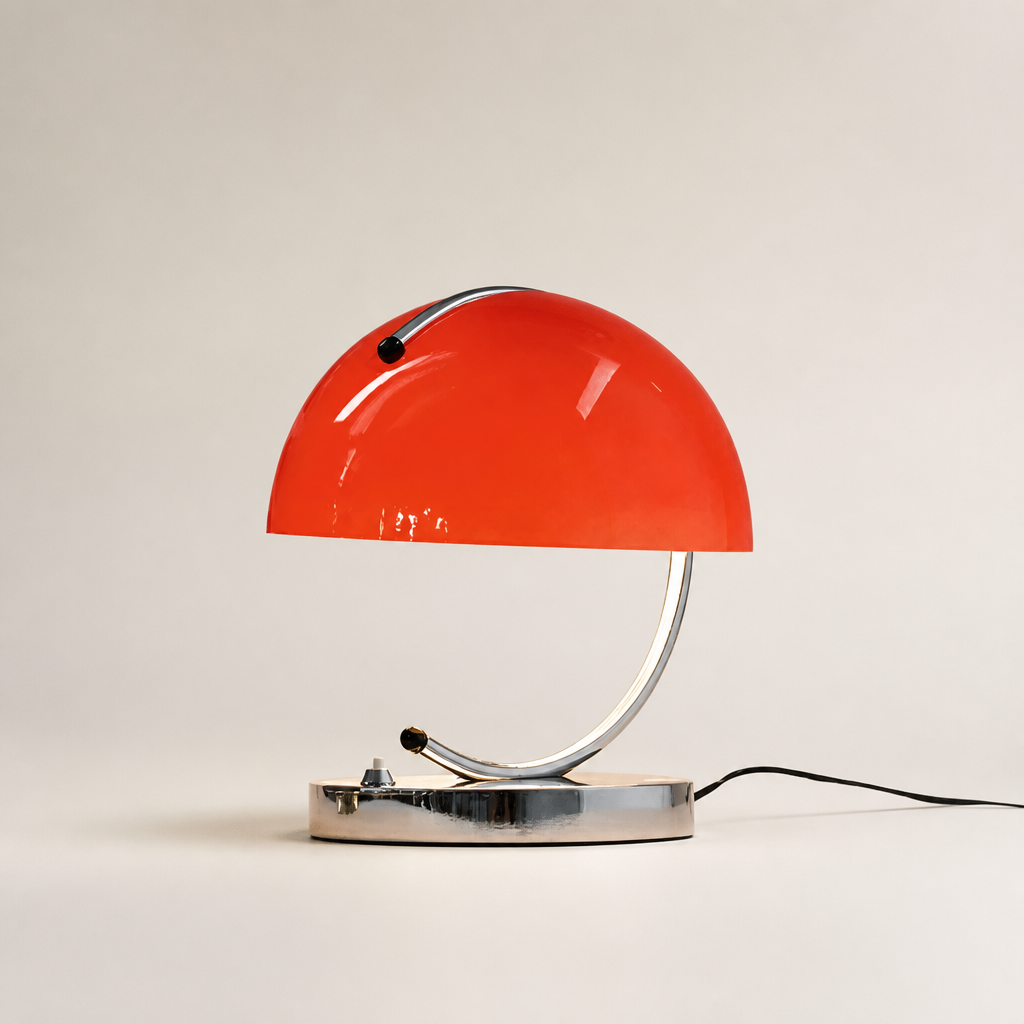 Glossy red dome table lamp with chrome curved stem and base on a neutral background.