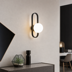 Black oval wall sconce with a glowing white globe above a modern console.