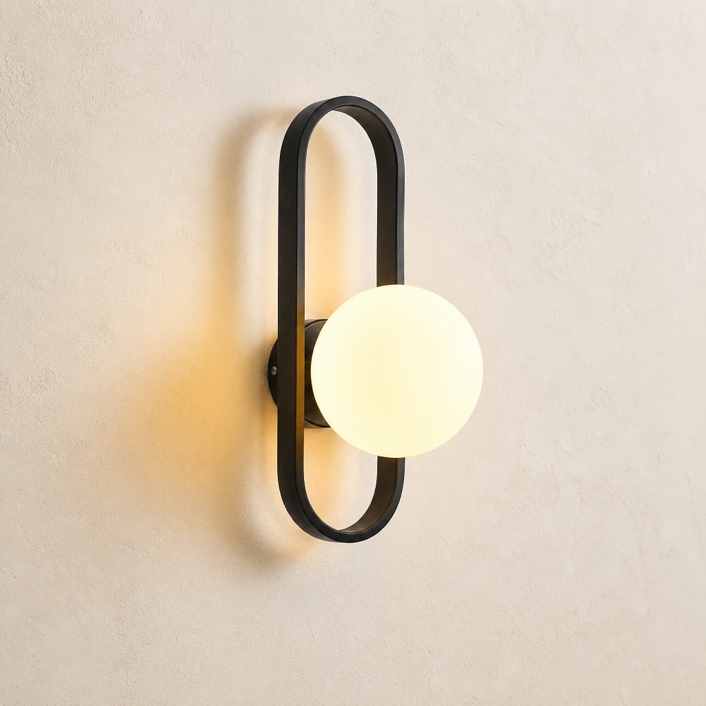 Modern wall sconce with a black oval frame and glowing round globe on a light textured wall.