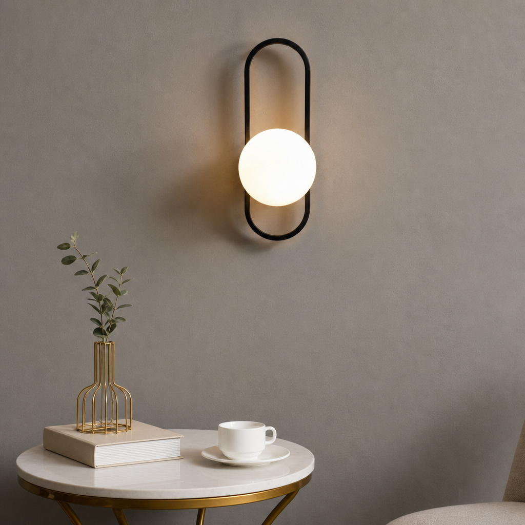 Black oval wall sconce with a glowing white globe above a minimalist side table.
