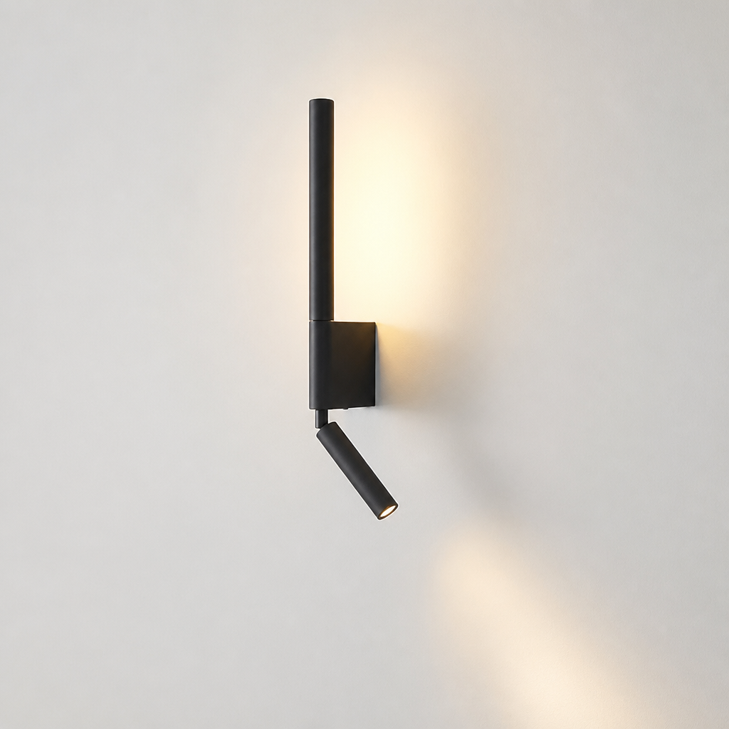Black modern wall sconce with vertical tube and angled spotlight glowing on a pale wall.