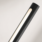 Black cylindrical light fixture with a warm vertical illuminated strip on a pale background.