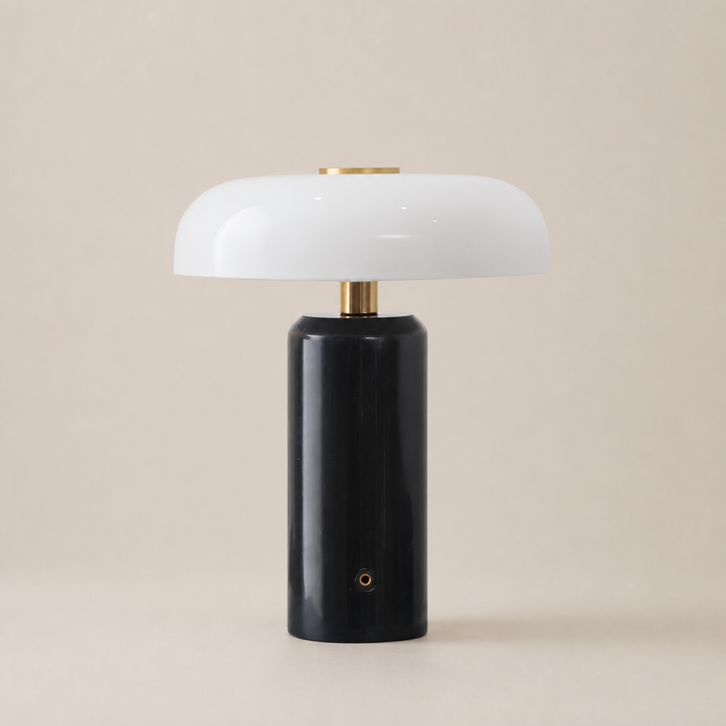 Glossy black cylindrical table lamp with a white rounded shade and brass accents.