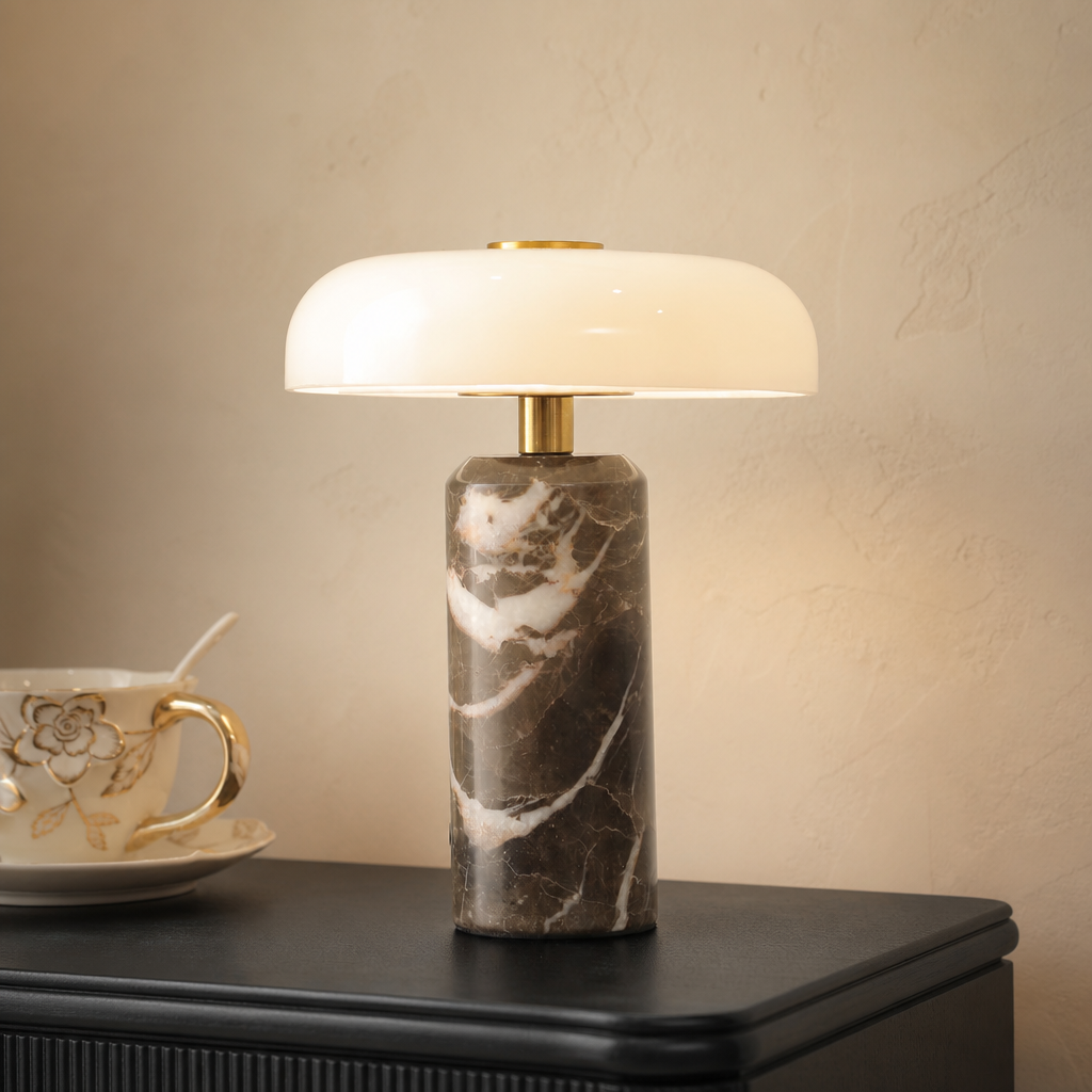 Brown marble table lamp with a glowing white shade and brass accents on a dark tabletop.