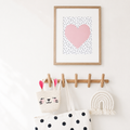 Wooden wall rack with framed pink heart print, bags, and woven rainbow decor on a white wall.