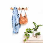 Wooden wall coat rack holding a denim jacket and tan leather shoulder bag.