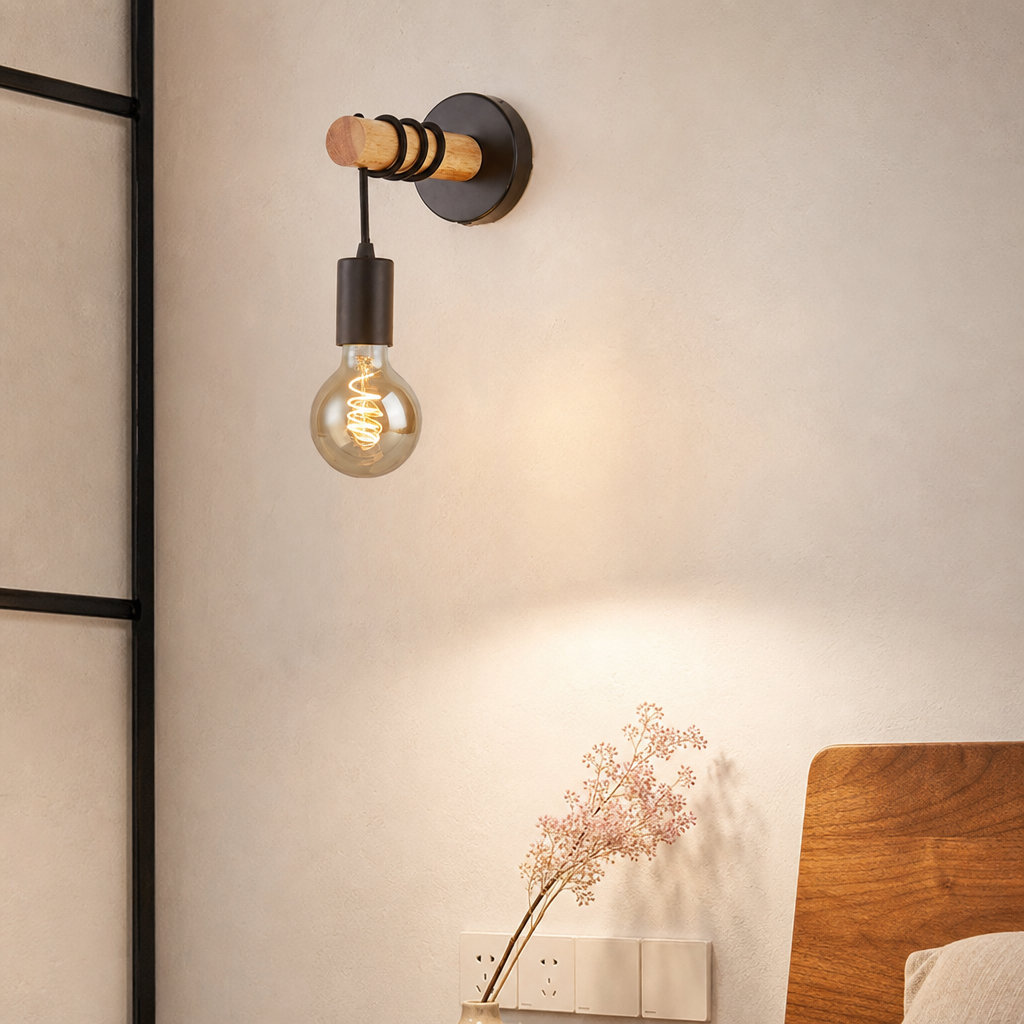 Wall-mounted wooden and black metal sconce with a glowing exposed bulb above a bedside wall.