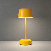 Glossy yellow cordless table lamp with a dome shade on a light tabletop.