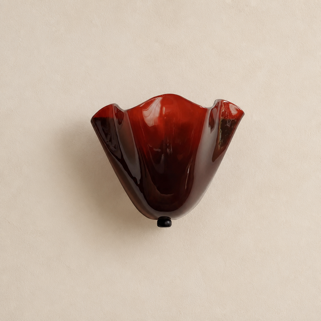 Glossy deep red wavy glass wall sconce centered on a warm neutral wall.