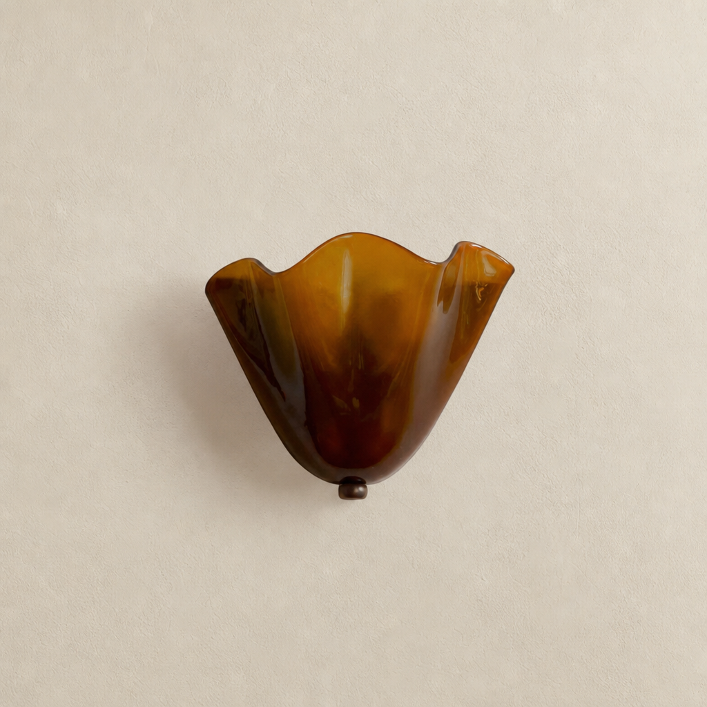 Amber fluted glass wall sconce with wavy rim on a neutral plaster wall.