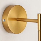 Brushed gold wall sconce mount with round backplate and horizontal arm on a plain light wall.