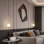 Two gold teardrop pendant lights glowing beside a gray sofa in a modern living room.