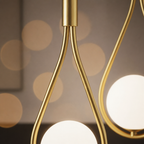 Brass chandelier detail with glowing white glass globes and curved gold arms.