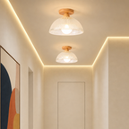 Two warm ceiling lights with white ribbed shades and wood mounts in a modern hallway.