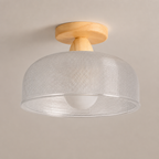 Flush mount ceiling light with wood base and translucent textured drum shade.