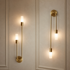 Gold wall sconces with glowing frosted cylindrical bulbs on paneled walls.