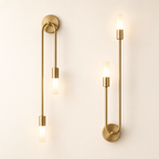 Two matching brass wall sconces with slim rods and glowing frosted cylindrical bulbs.