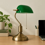 Green banker’s desk lamp beside a laptop