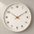 Minimal white wall clock with black numerals and wooden hands on a pale wall.