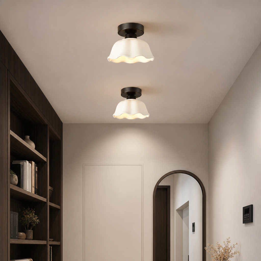Two cream wavy glass flush mount ceiling lights in a modern hallway with a bookshelf and arched mirror.