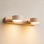 Two-light wooden wall sconce with speckled stone shades casting a warm glow.