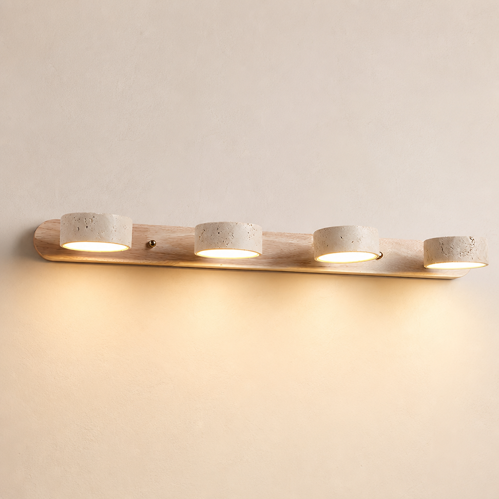Four-light wooden vanity fixture with stone-textured round shades glowing warm on a pale wall.