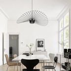 Black wire fan-shaped pendant lamp hangs above a white dining table in a bright minimalist room.