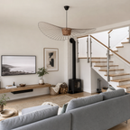 Sculptural wire pendant light above a neutral living room with stairs.