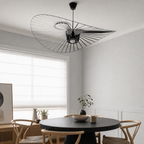 Black wire pendant lamp with a wide sculptural shade above a round dining table.