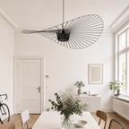 Black wire pendant light shaped like a sweeping leaf in a bright minimalist room.