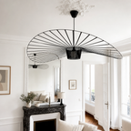Black wire fan-shaped pendant light hanging in a bright white living room.