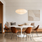 Glowing ribbed white oval pendant lamp above a modern dining table.