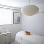White ribbed paper pendant lamp hanging in a bright minimalist bedroom.