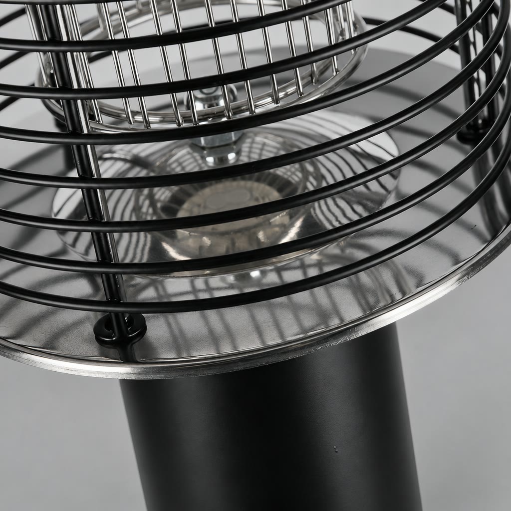 Close-up of a black metal cage heater with reflective chrome dish and cylindrical base.