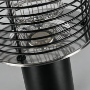 Close-up of a black metal cage heater with reflective chrome dish and cylindrical base.