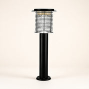 Black outdoor post lantern with a clear caged lamp head and round base.