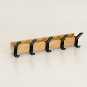 Wooden wall-mounted coat rack with five black double hooks.